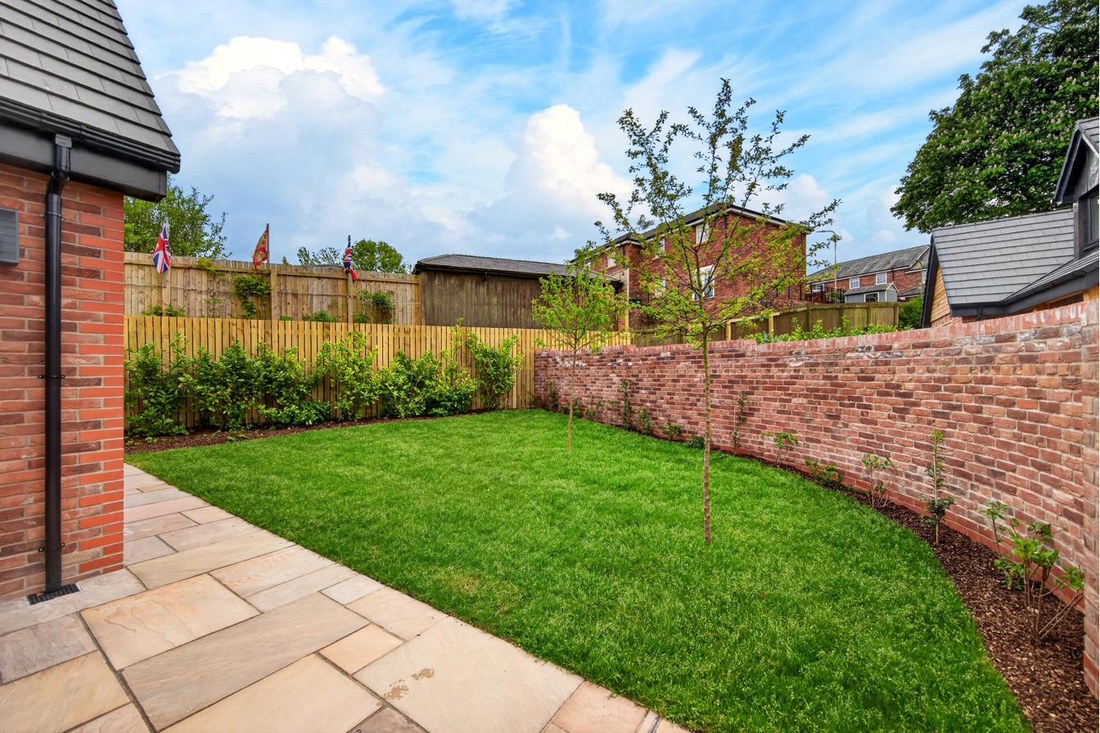 Private brick-walled rear garden with manicured lawn.